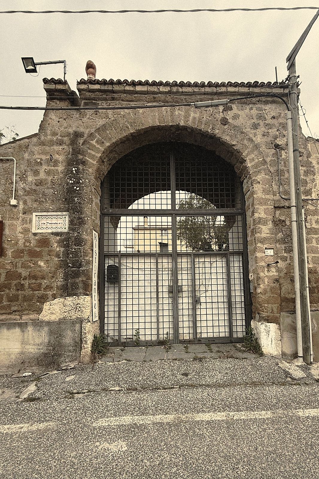 Il portale antico in tufo della dimora, visto dalla strada all'imbrunire